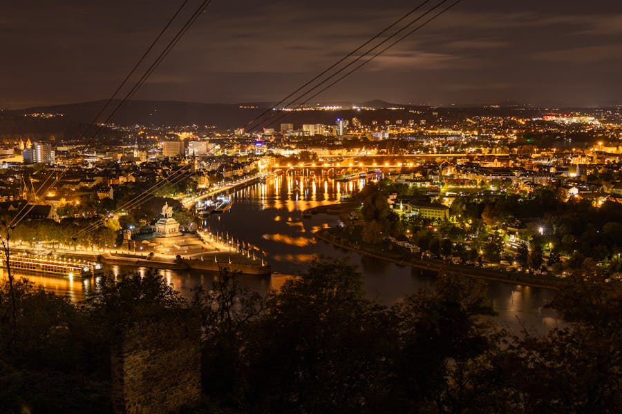 Koblenz by night, the city is lighted beautifully, in the front you can see the rivers Rhine and Moselle, as well as the Deutsches Eck, where both rivers flow into each other.