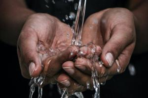 Hände, geformt zu einer Schale, fangen Wasser auf