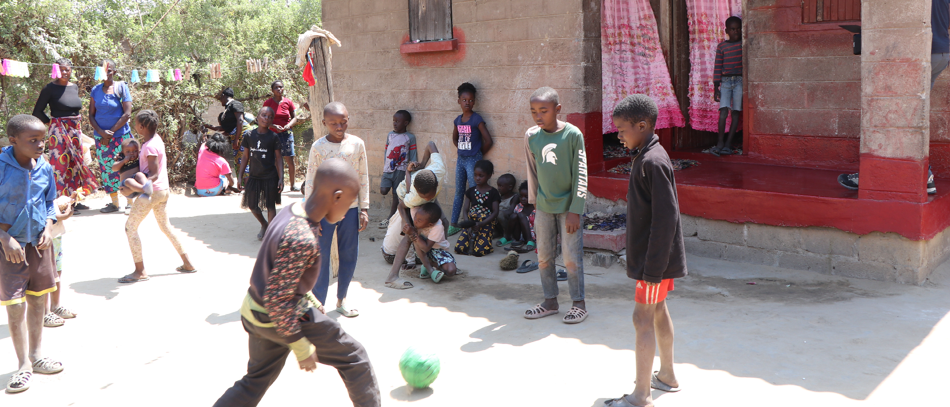 Spielende Kinder vor einem Haus in Sambia bei Sonnenschein