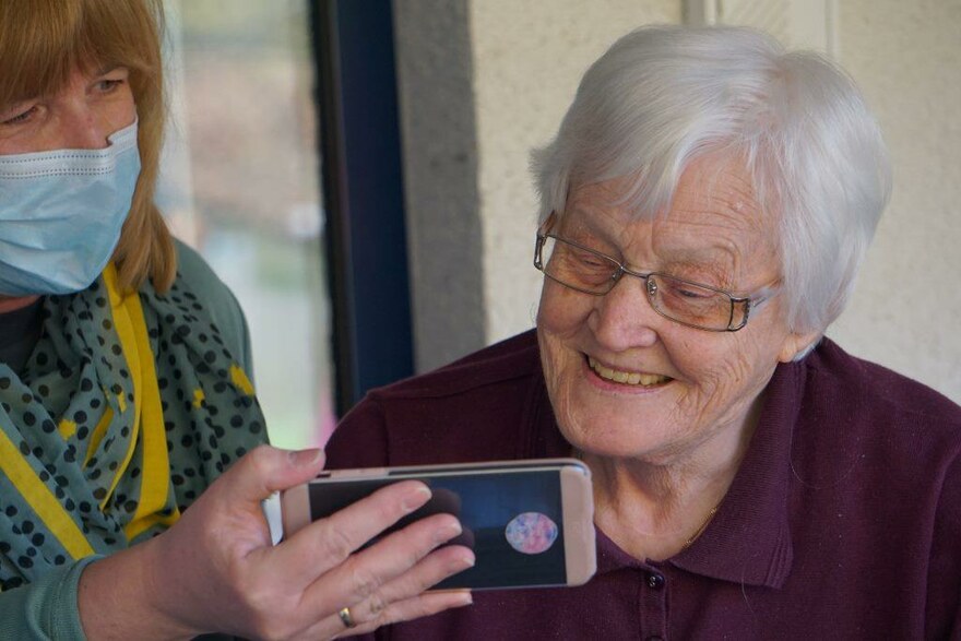 Eine Seniorin bekommt Bilder auf einem Smartphone gezeigt